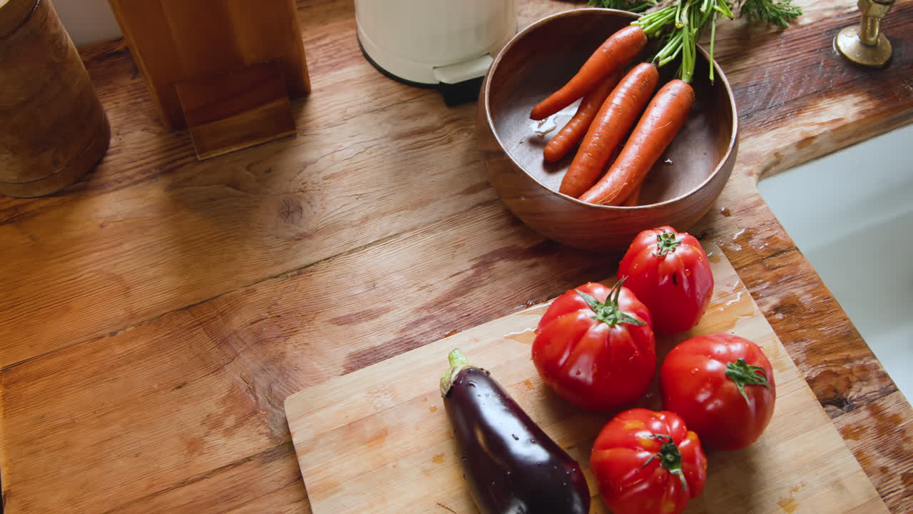 Fresh tomatoes, eggplant, and carrots on wooden cutting board in kitchen, at home, copy space