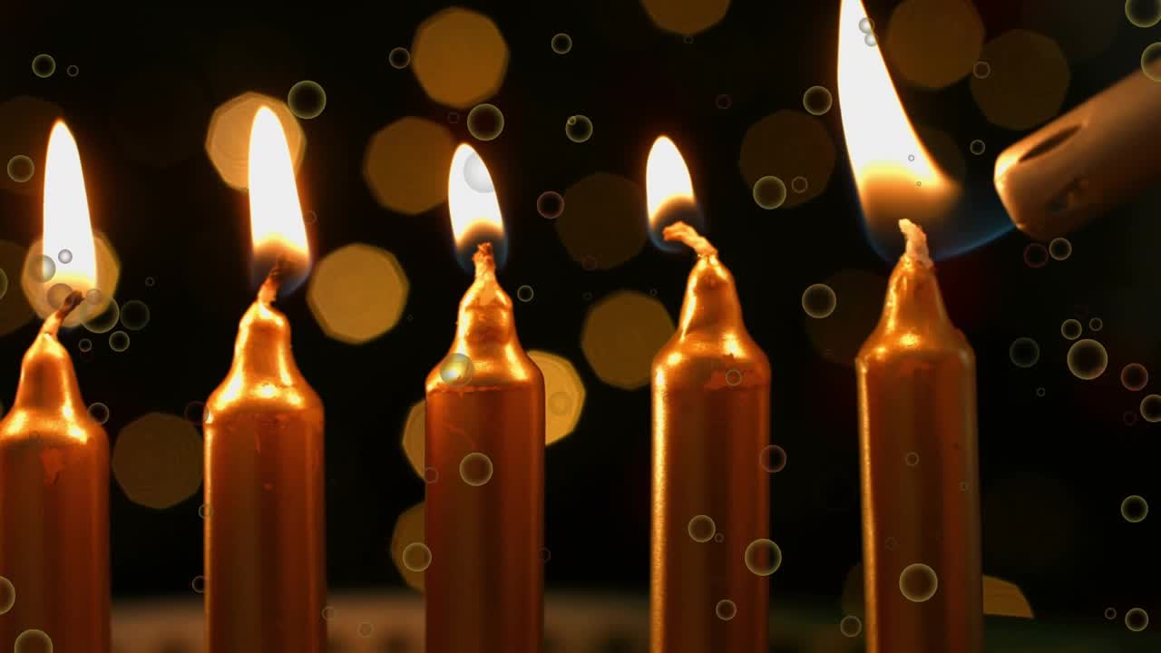 Entering lighter nozzle, igniting five gold taper candles one by one creating festive glow