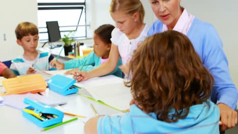 Teacher-helping-kids-with-their-homework-in-classroom