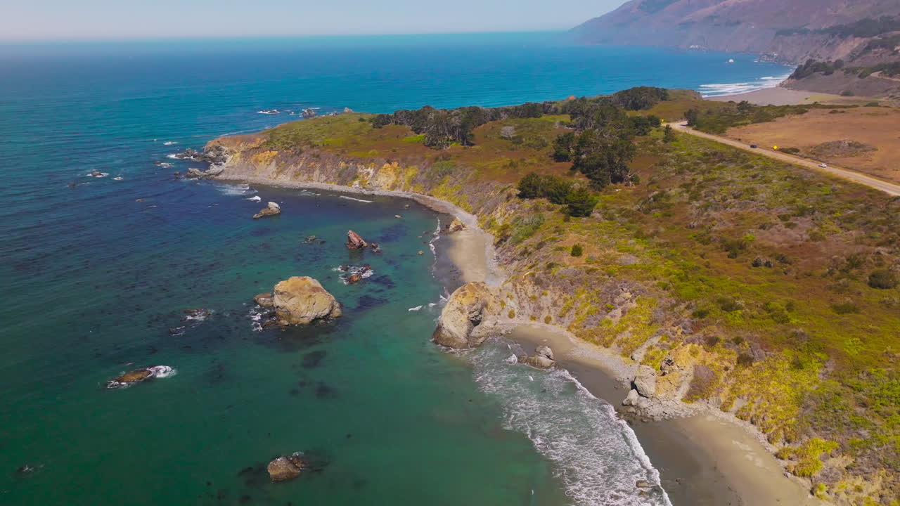 Beautiful rocky shore of the ocean with scarce vegetation. Calm ocean waters at mountainous coastline of Morro Bay, California, USA. Aerial view.