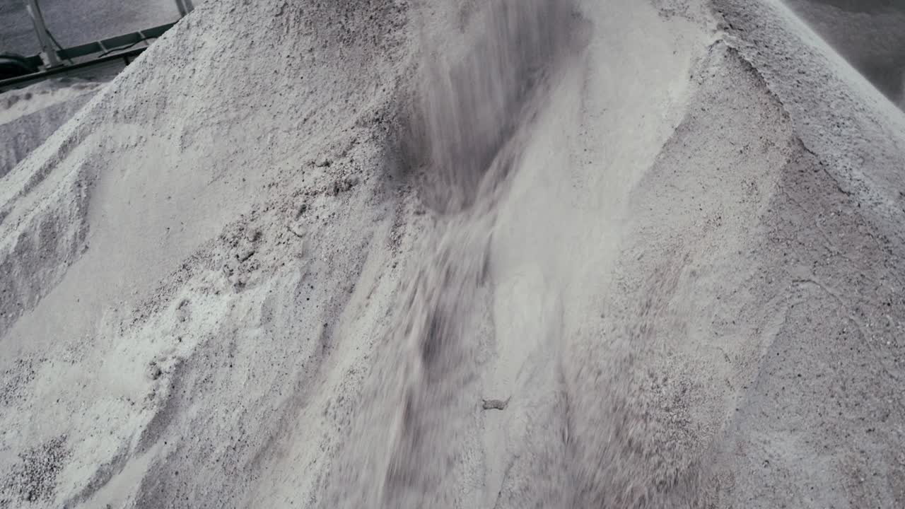 A top-down view of material being poured into a large quarry or processing facility, showcasing the scale and intensity of the operation.