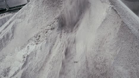 a top-down view of material being poured into a large quarry or processing facility, showcasing the scale and intensity of the operation.