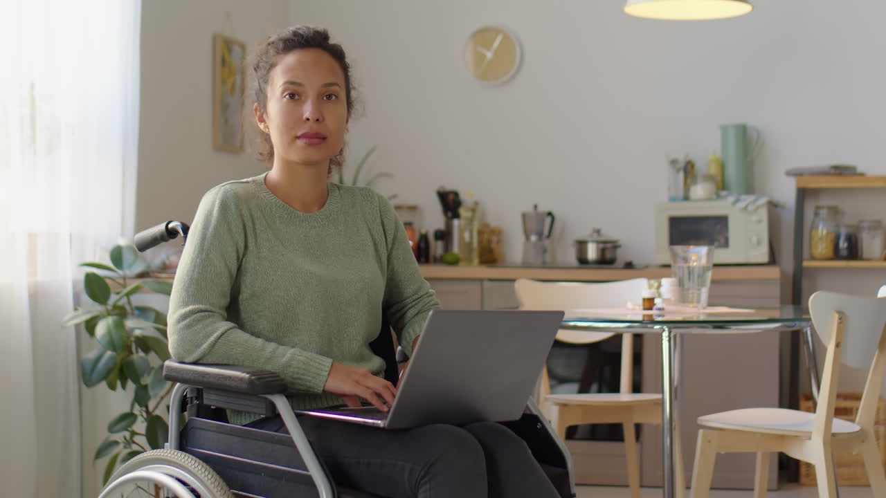 Woman in wheelchair working on laptop at home