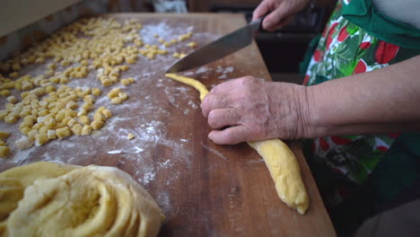 handmade preparation of struffoli with hand of woman cutting dough