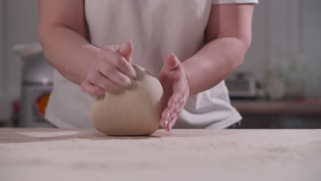 female hands knead and toss dough on kitchen