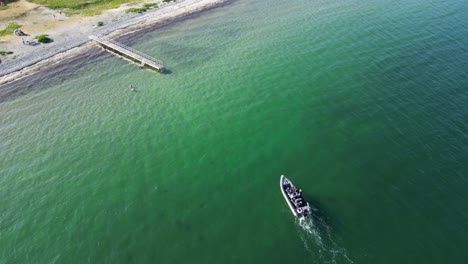 Imágenes-De-Drones-De-Una-Lancha-A-Motor-Navegando-Hacia-La-Playa-Para-Amarrar-En-Un-Embarcadero