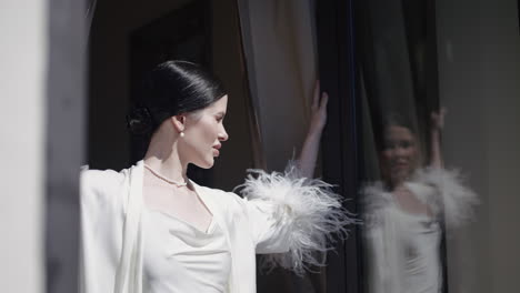 woman in a white robe by the window