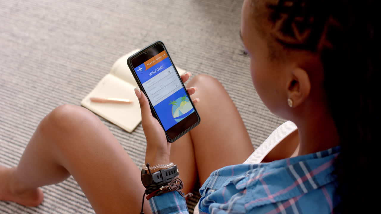 A young African American woman booking travel on her smartphone
