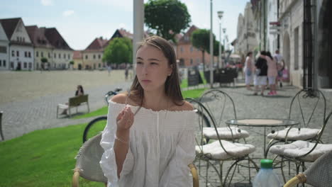 young woman enjoying a dessert in a charming european city square