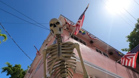 spooky skeleton against festive pink building with usa flags