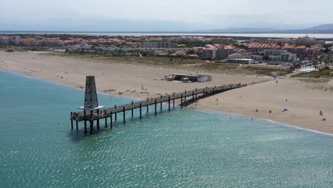 Vuelta-Aérea-Viajando-Sobre-Un-Pontón-De-Madera-Leucate-Francia-Playa-De-Arena-Mar