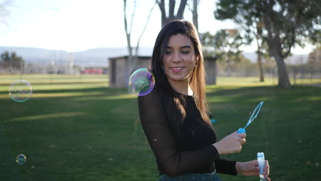 chica hispana soplando muchas burbujas de ensueño mientras sonríe y ríe con felicidad mientras aparece en cámara lenta