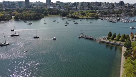 Drone-shot-of-False-Creek-during-summer-in-downtown-Vancouver-with-boats,-a-dock-and-buildings-in-the-shot