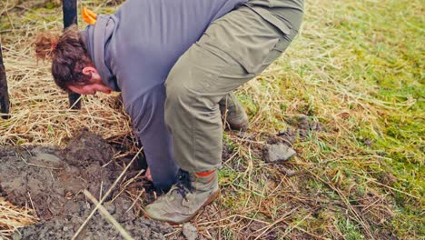 man digging holes while building traditional fence - close up