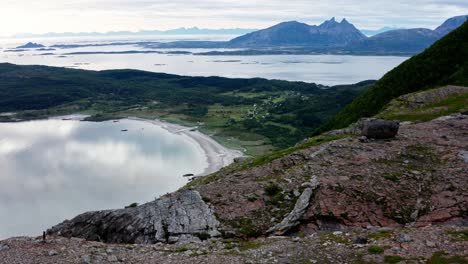 hombre caminando en la cima de una montaña rocosa con vistas al hermoso lago en noruega, drone aéreo