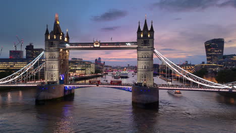 Two-red-London-buses-pass-each-other-over-London-Tower-Bridge,-twilight-aerial