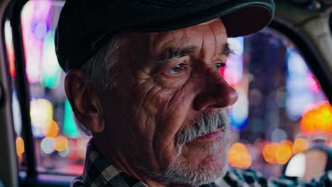 senior man driving a taxi at night in the city