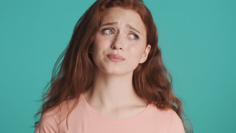 Redheaded-girl-in-front-of-camera-on-turquoise-background.