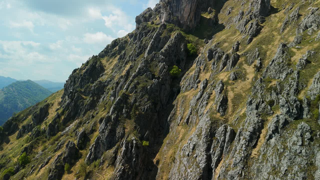 vista panorámica aérea de un pico de montaña rocosa con exuberante vegetación bajo un cielo azul claro, perfecto para los entusiastas del aire libre