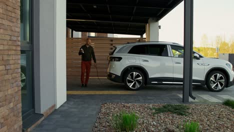 man charging electric suv at home