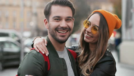 close-up view of young caucasian man standing in the street while his girlfriend coming up to him