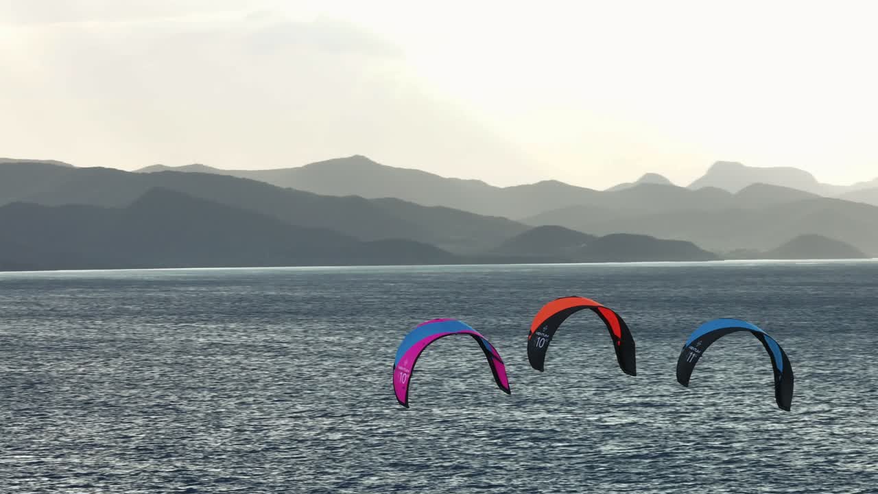 바다 위에서 카이트보드를 타고, 배경에는 산이 있습니다.