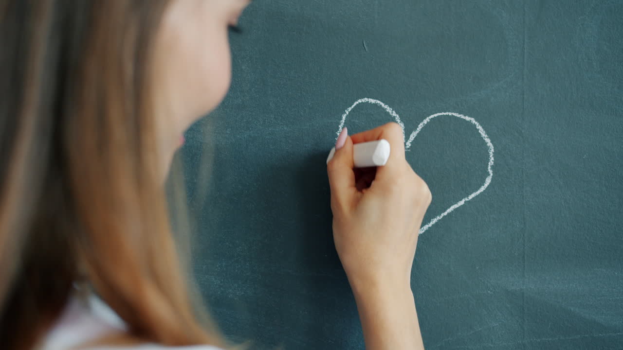 Woman drawing a heart on a chalkboard
