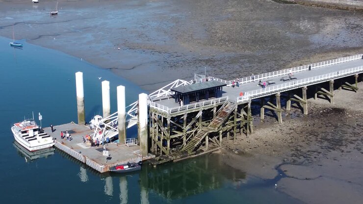 Sunny Beaumaris pier aerial view relaxing seaside waterfront tourist attraction Welsh landmark push in orbit right