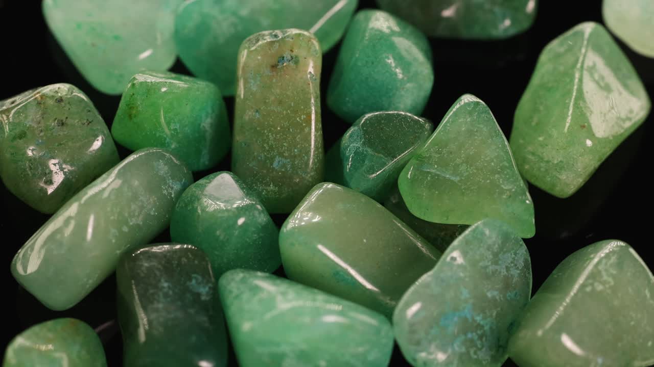 A close-up view of polished green aventurine stones with subtle lighting changes over 11 seconds