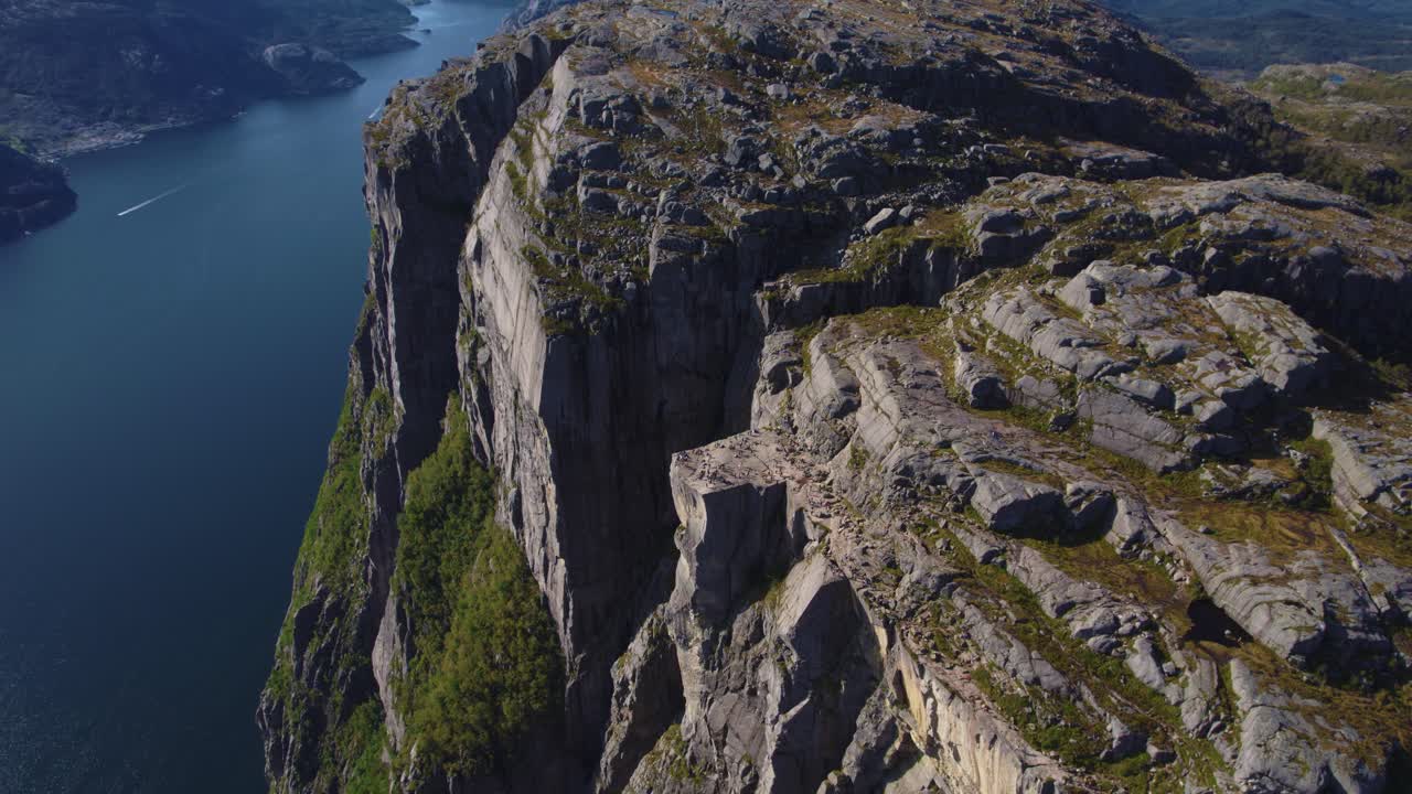 Preikestolen plateau with visitors, wide panoramic view of steep cliffs and Lysefjord. Cinematic drone