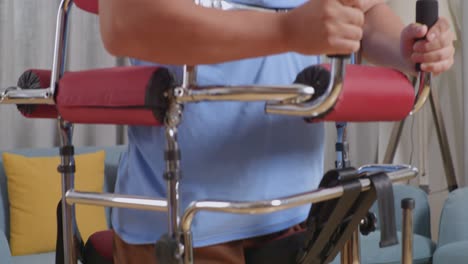 close up side view of asian male patient trying to walk by walker during a physical therapy at home