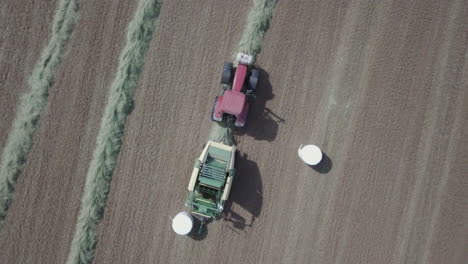 Equipo-Industrial-Empaquetando-Balas-De-Heno-En-Plástico-Blanco,-Vista-Aérea-De-Arriba-Hacia-Abajo