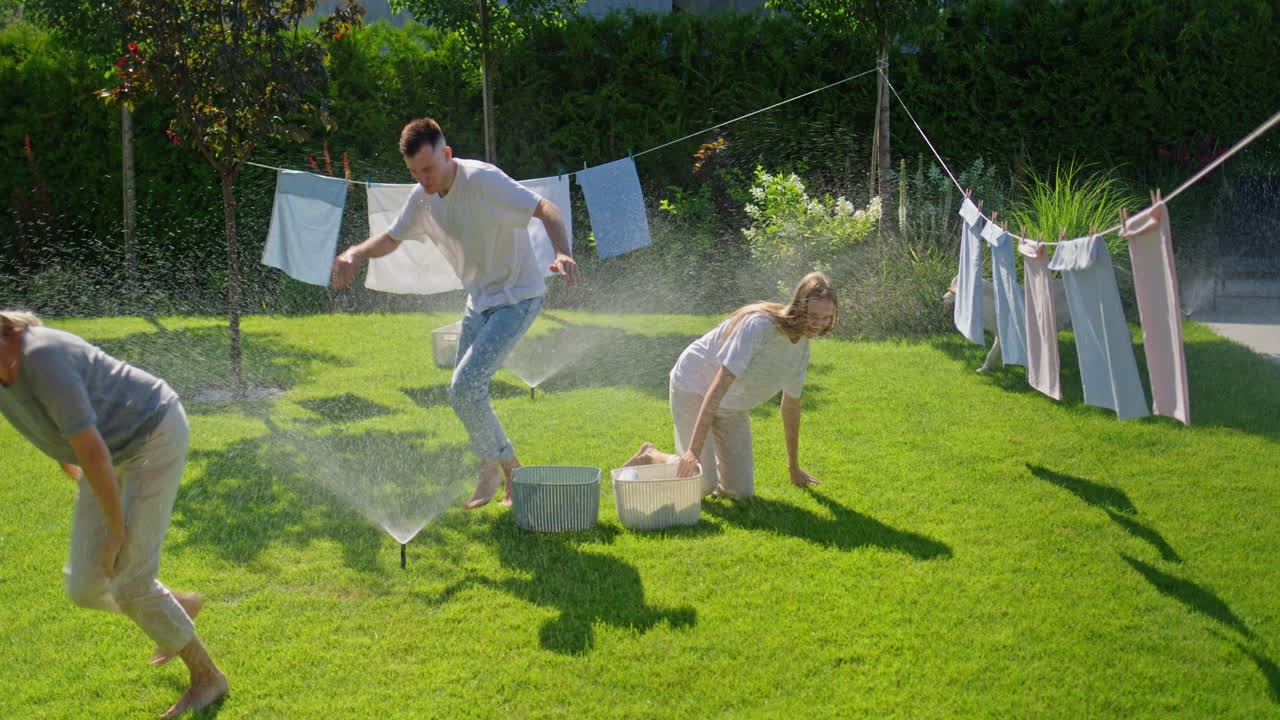 스프링클러 를 가지고 정원에서 즐거움을 즐기는 부부