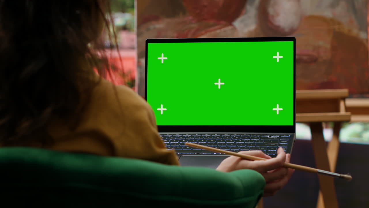 Artist using laptop with green screen
