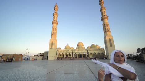 puesta de sol, amanecer vista de la mezquita de el mina con mujer en largo vestido blanco y hijab disfrutando de la vista de la mesquita
