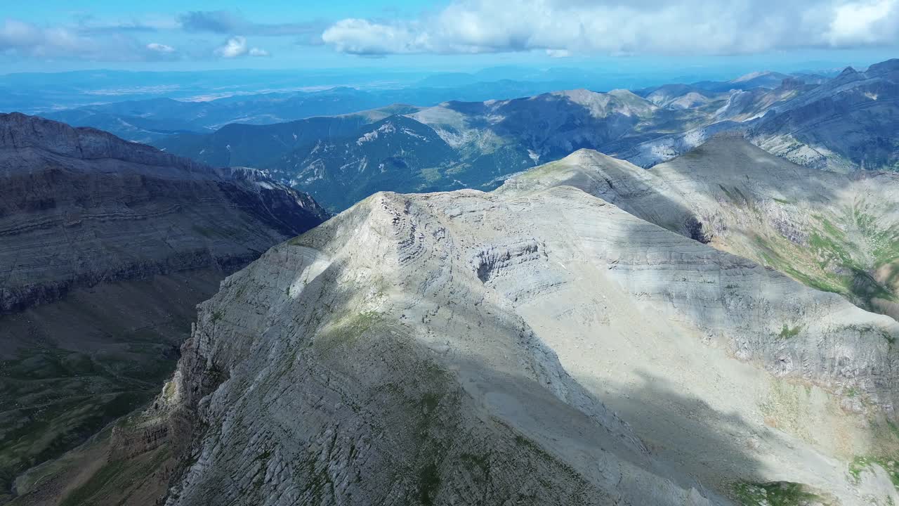 Drone footage of rugged mountain peaks in Valle de Ip near Canfranc, Aragón, Spain. Dramatic lighting casts shadows on rocky textures, creating a breathtaking aerial landscape