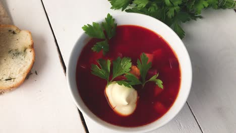 a girl breaks soft fresh bread near a plate of vegetable beet soup