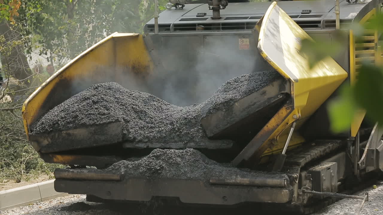 Costruzione e riparazione stradale. Finitrice cingolata durante i lavori di pavimentazione in asfalto per una strada in costruzione
