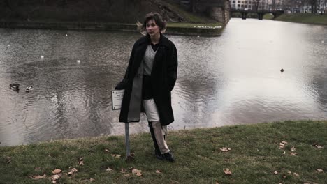 Young-woman-in-a-black-coat-standing-in-a-park-with-a-sea-in-autumn-in-afternoon