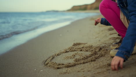 kid hands drawing sand beach at sea vacation. little girl play on nature outside