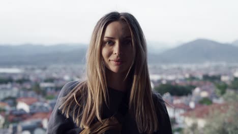 Blonde-woman-look-straight-to-camera-while-standing-at-nice-viewpoint