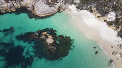 drone aerial panning down over secluded beach with bright blue water in australia