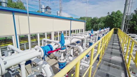 walking over a bridge in middle of pipelines at a natural gas compressor station, sunny day