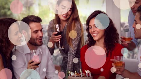 animation of white dots over happy diverse female and male friends drinking wine and talking