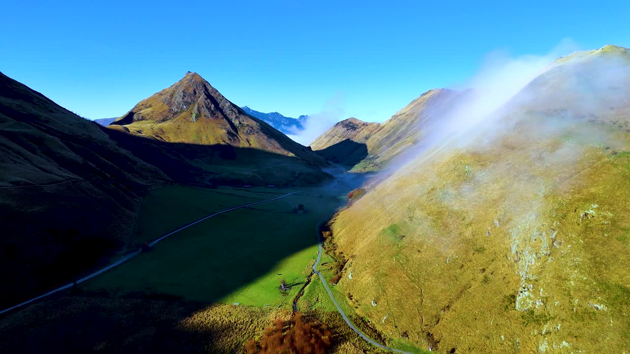 Aerial view of fog moving over Moke Lake, Queenstown, with clear skies and mountainous terrain. Captured in vibrant daylight