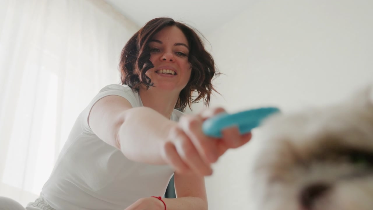 Mujer sonriente jugando con su perro mascota en el interior