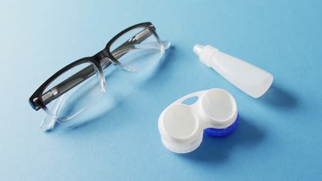 Video-of-pair-of-glasses,-contact-lenses-case-and-solution-on-blue-background