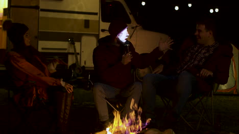 hombre barbudo contando una historia aterradora a sus amigos alrededor del fuego del campamento