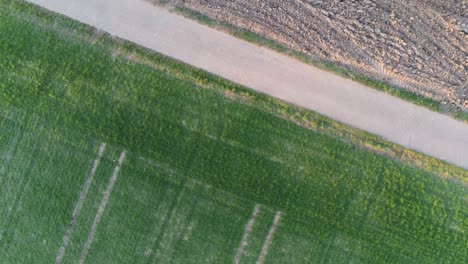 Rotation-top-view-of-paved-road-and-agricultural-field-in-Germany,-Europe