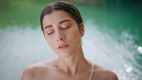 relaxed woman breathing deeply doing yoga exercise at turquoise lake closeup